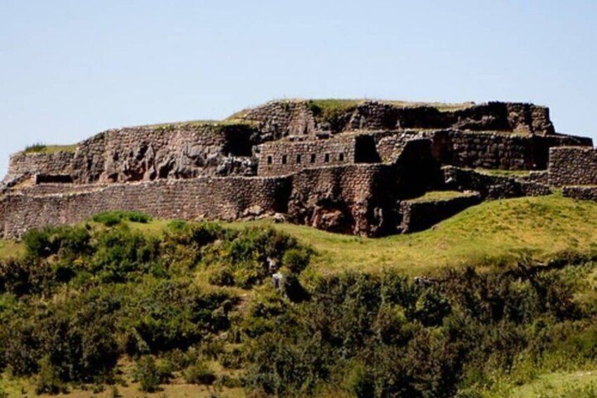An ancient stone structure on a grassy hill. 1