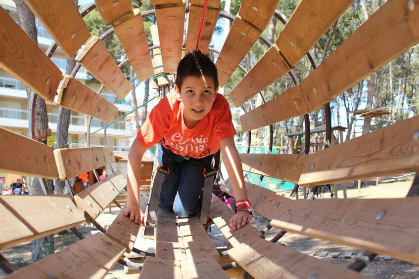 A person climbing a wooden climbing structure outdoors. 2