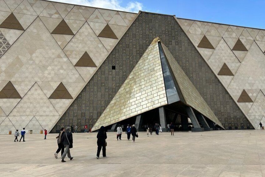 A large pyramid-shaped building with a tiled facade and a spacious plaza in front. 3