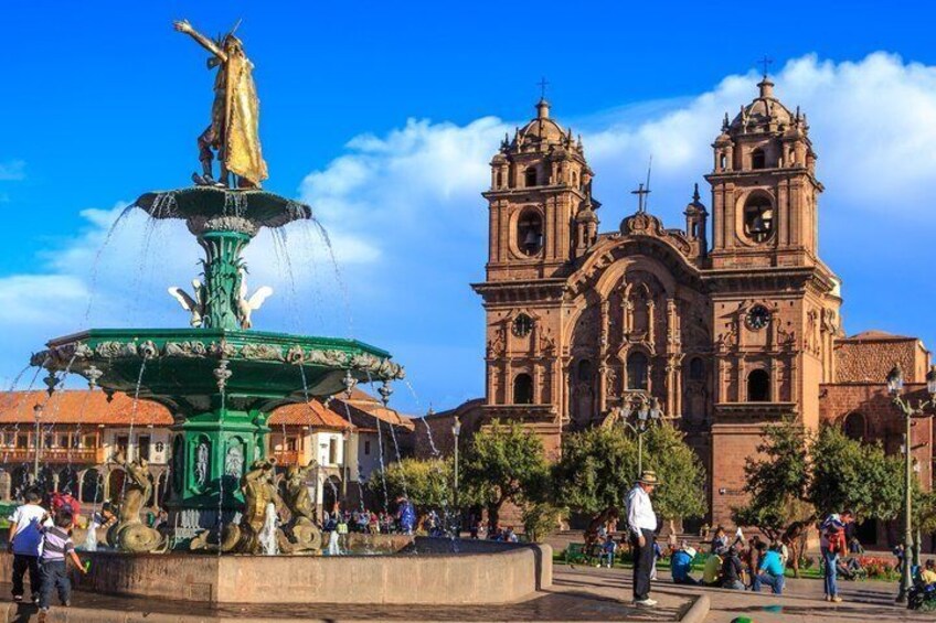 A historic church with twin bell towers and a fountain with a statue. 5