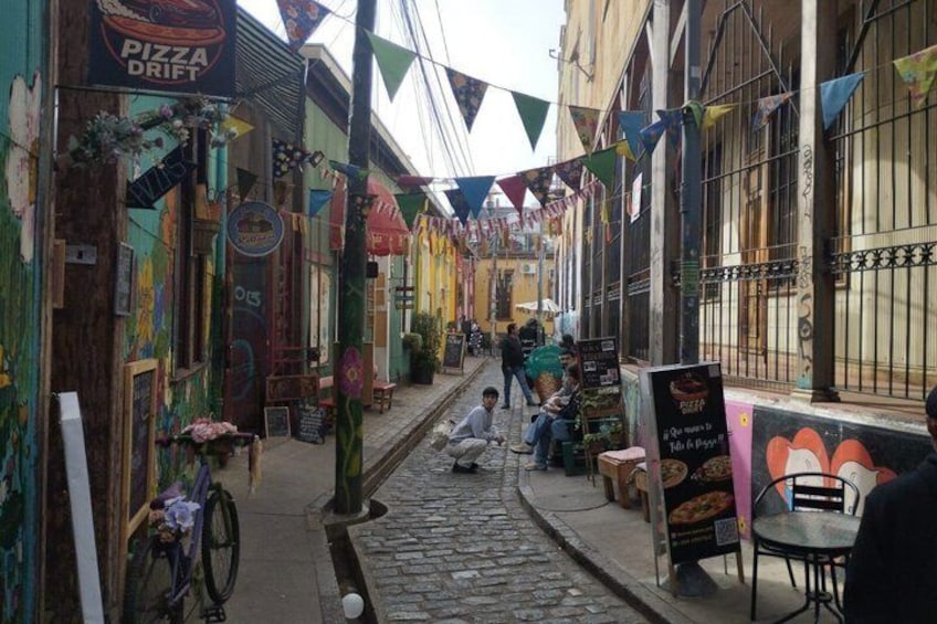 A narrow street with colorful buildings, a pizza shop, and a bicycle. 4