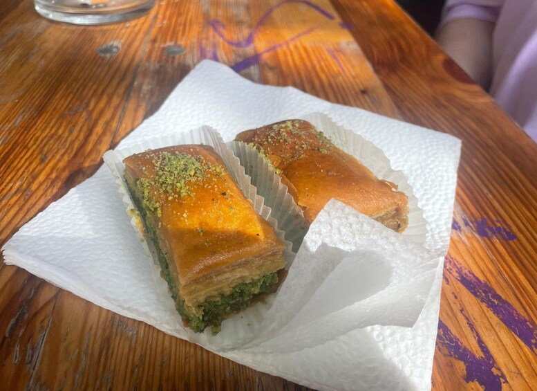 Two pieces of baklava on a white paper napkin on a wooden table. 3