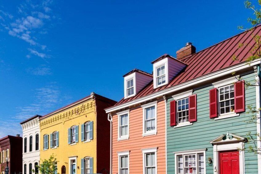 A row of colorful houses with red shutters and a clear blue sky. 1