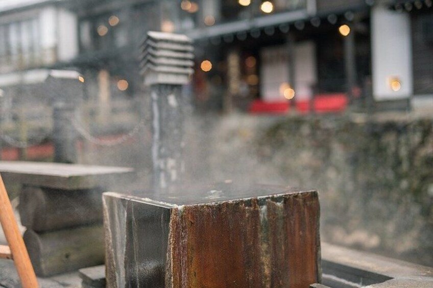A rustic metal structure, possibly a part of a building's exterior, with a blurred background featuring a building with lights. 2