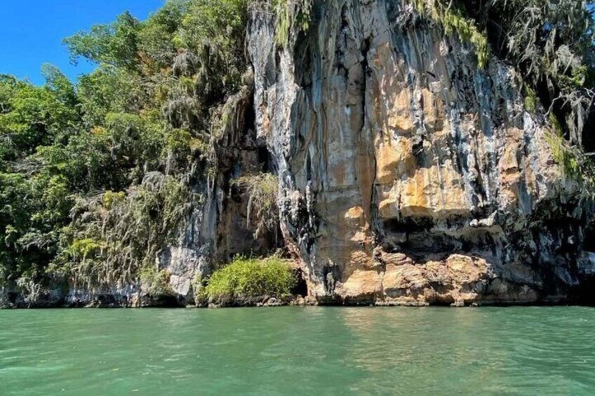 A limestone cliff with a clear water body in front. 1
