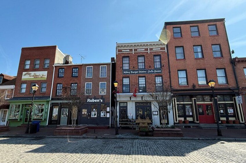 A cobblestone street with brick buildings, including a restaurant named 'Ruben's' and a diner called 'Abbey's Burger Bistro.' 4