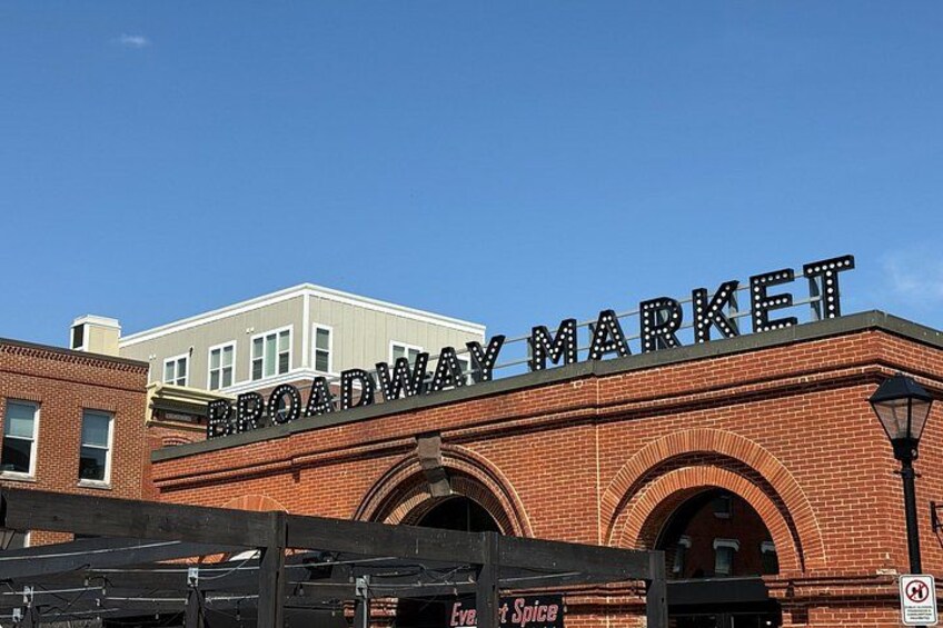 A brick building with the sign 'BROADWAY MARKET' above the entrance. 5