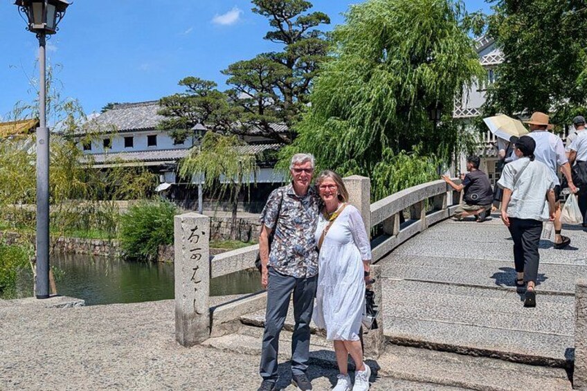 A stone bridge, a pond, and traditional Japanese architecture in the background. 3