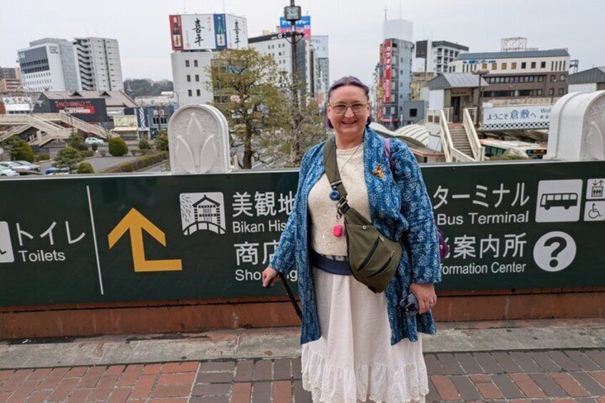 A person standing in front of a sign with 'Bikan Historical Shopping Center' and 'Toilets' directions. 4