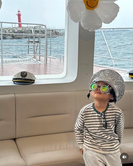 Ein Kind in einem Boot, das ein gestreiftes Hemd und eine Kappe mit Sonnenbrille trägt. 4
