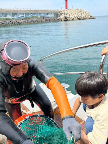 A person in a wetsuit and diving mask handling a net on a boat. 4