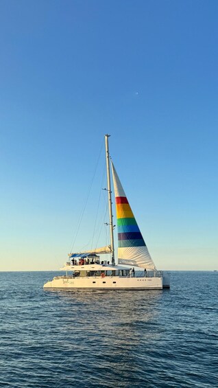 A sailboat with a rainbow sail on the water. 1
