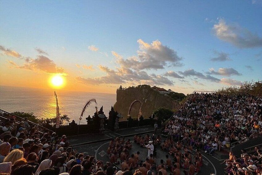 Un coucher de soleil sur une zone côtière, avec une foule rassemblée sur une scène. 3