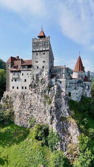 A historic castle perched on a rocky cliff, surrounded by lush greenery. 4