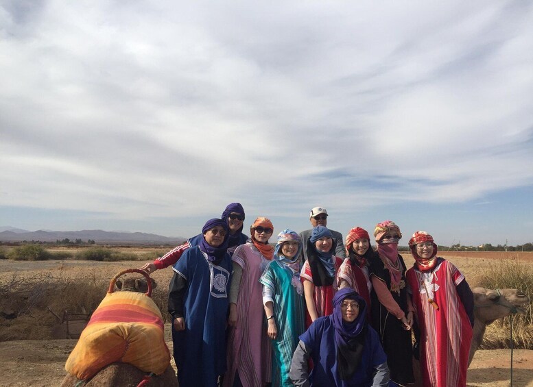 A group of people in traditional attire posing in a desert landscape with mountains in the background. 2