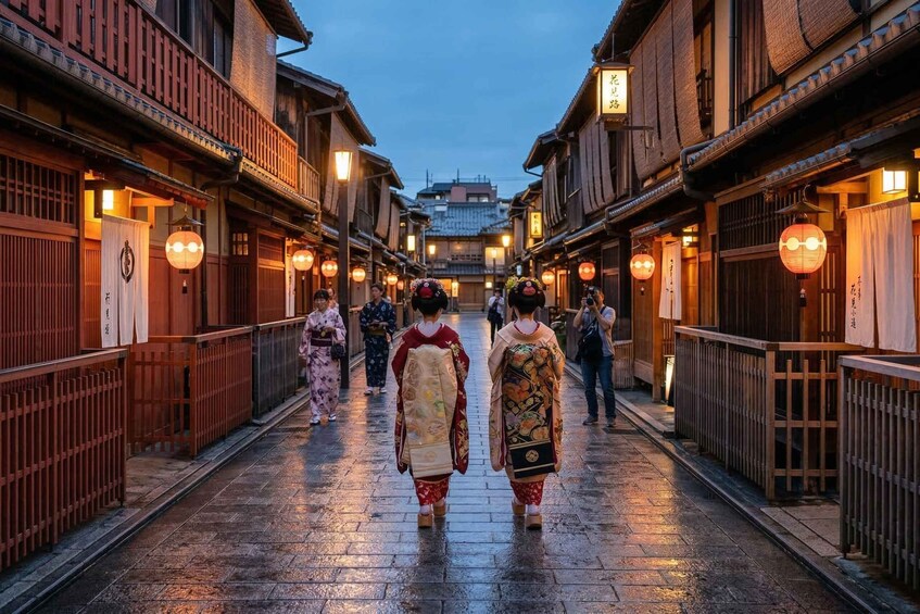 A traditional street with wooden buildings, lanterns, and people in traditional attire walking down the path. 4