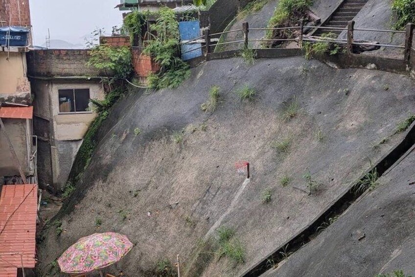 A steep, grassy slope with a staircase on the left and a concrete wall on the right. 3