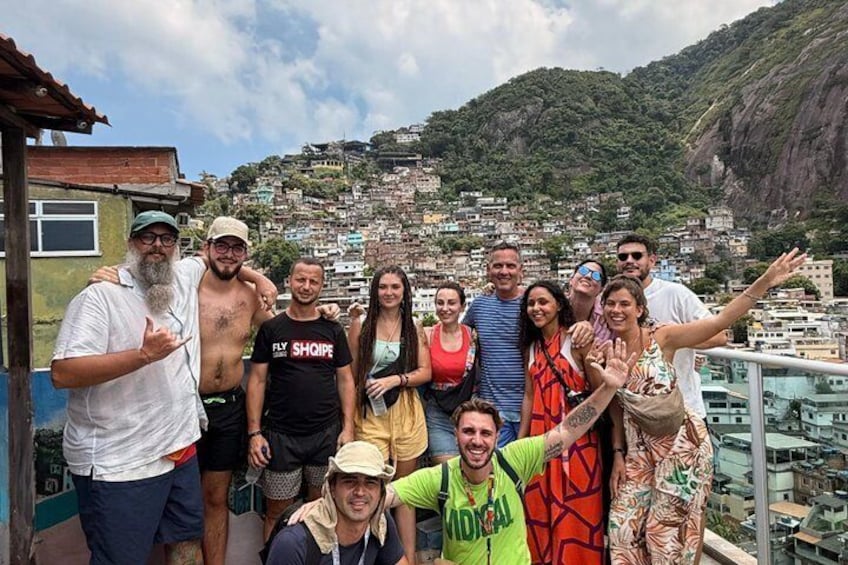 A group of people on a balcony overlooking a densely populated hillside cityscape. 1