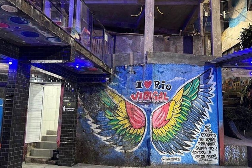 A mural with the text 'I ♥ Rio Vidigal' and a pair of colorful wings. 4