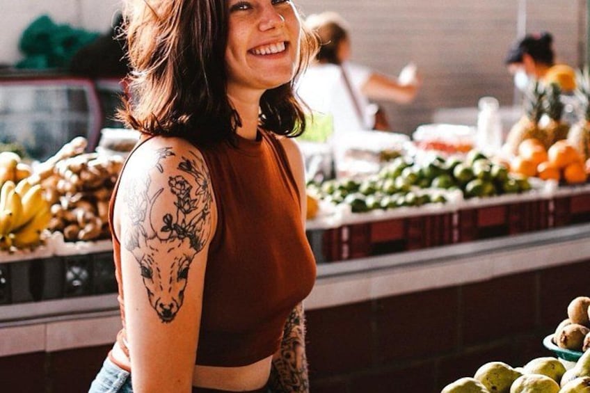 A person with a tattoo on their arm standing in front of a produce display. 1