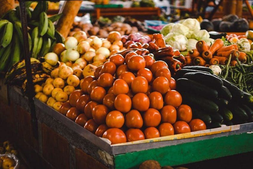 A market stall with tomatoes, bananas, and various vegetables. 4