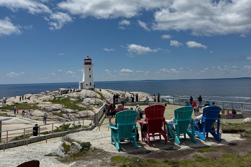 A lighthouse, chairs, rocky terrain, and the ocean. 1