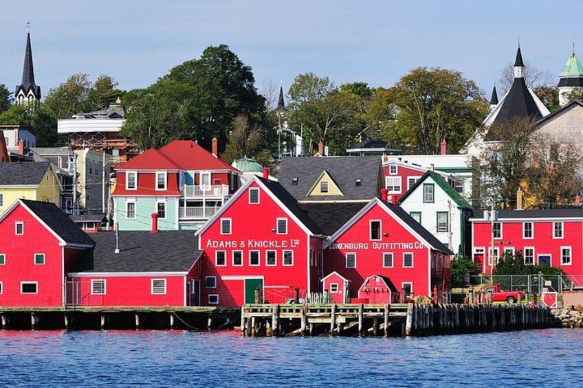 A waterfront with colorful buildings, including a red building with 'Adams & Knickle' signage. 3