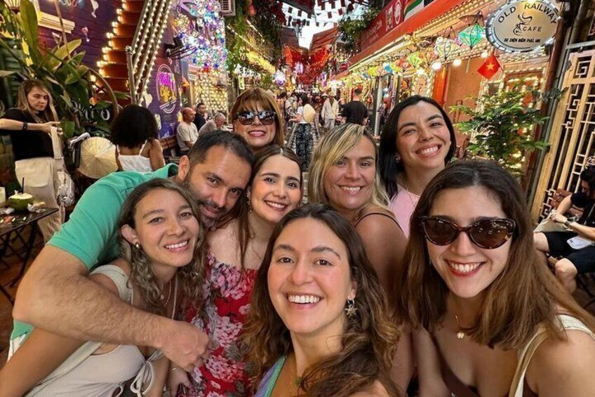 A group of people in a crowded, brightly lit street with shops and decorations. 1
