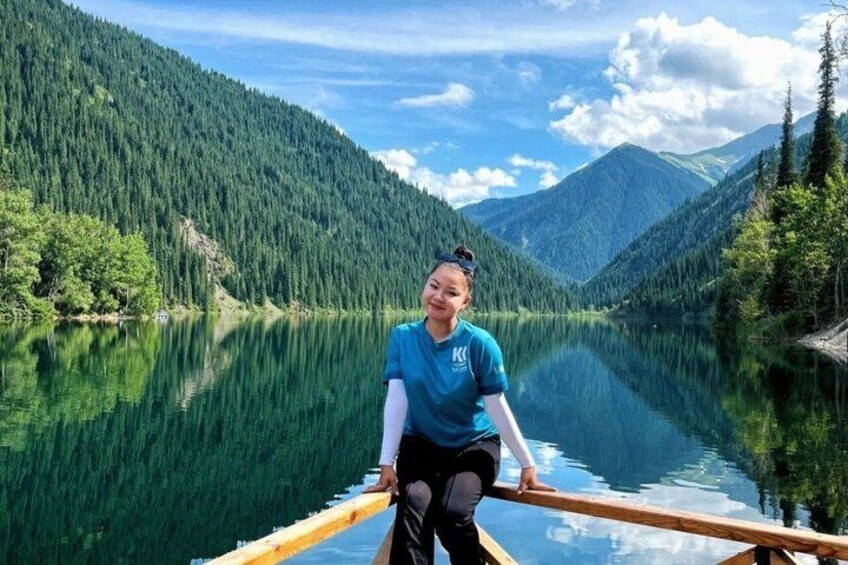 A person on a paddleboard in a calm lake surrounded by dense forest and mountains. 4