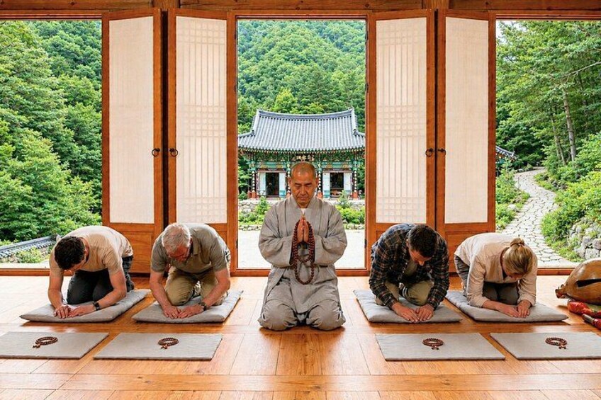 Four people in a traditional Japanese setting, performing a seated meditation or yoga pose. 1