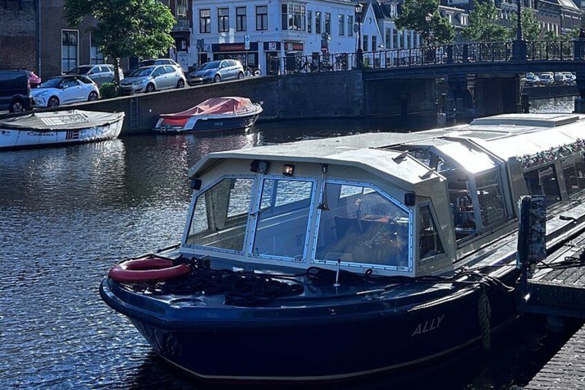 A narrowboat docked at a canal, with a bridge and buildings in the background. 2