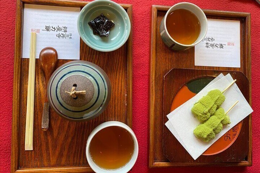 A traditional Japanese tea ceremony setup with a wooden tray, a tea pot, a cup of tea, a bowl of matcha, and a pair of chopsticks. 4