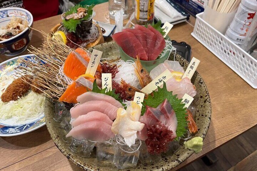 A variety of fresh seafood on a wooden platter, including fish, shrimp, and roe, with labels indicating their names. 5