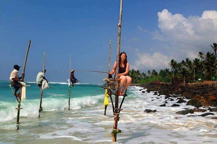 People fishing from a pier in the ocean with palm trees in the background. 1