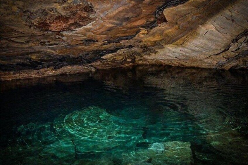 A cave interior with clear water and rock formations. 2