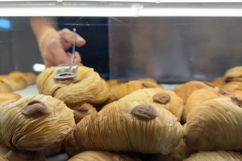 A display of pastries with a hand using a tool to interact with them. 4