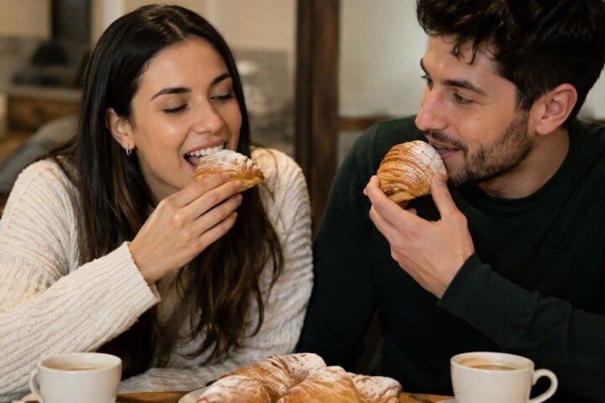 Two people sitting at a table with croissants and coffee cups. 3