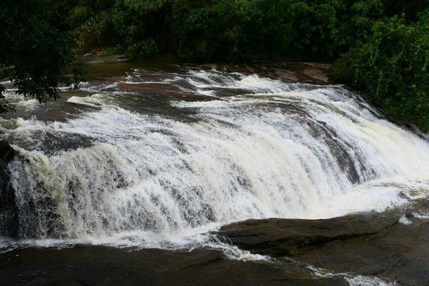 A waterfall cascading over rocks surrounded by dense greenery. 5