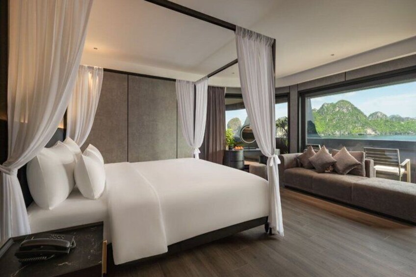 A modern bedroom with a large bed, a sofa, and a view of a mountainous landscape. 1