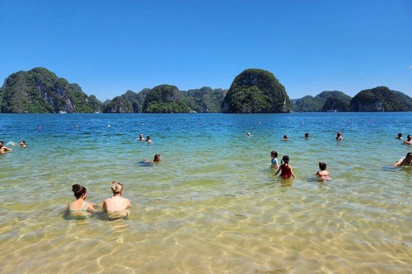 People swimming in a clear blue sea with green islands in the background. 5