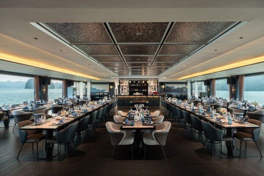 A restaurant with tables set for dining, a bar area, and a view of the sea. 4