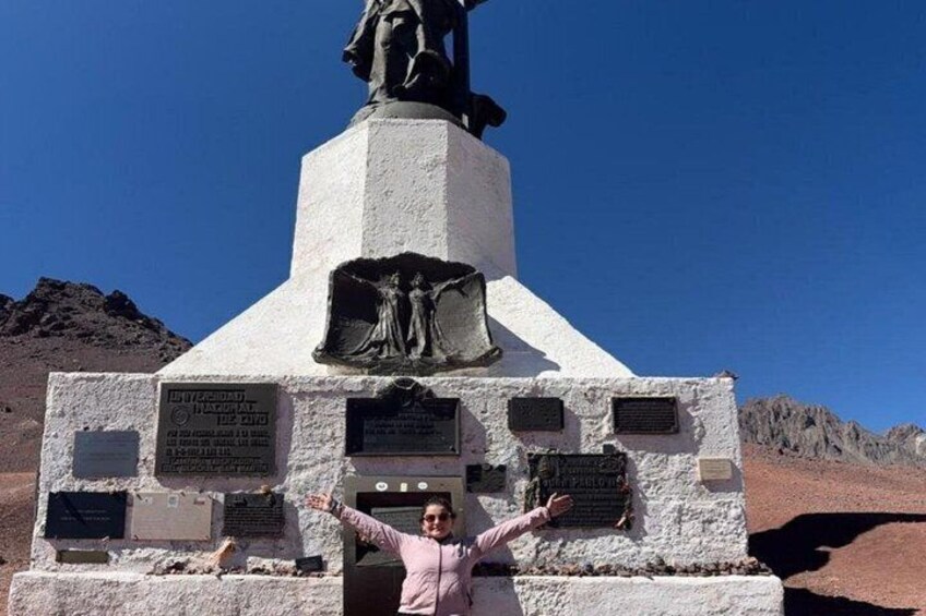 A person standing in front of a monument with inscriptions and a statue on top. 4