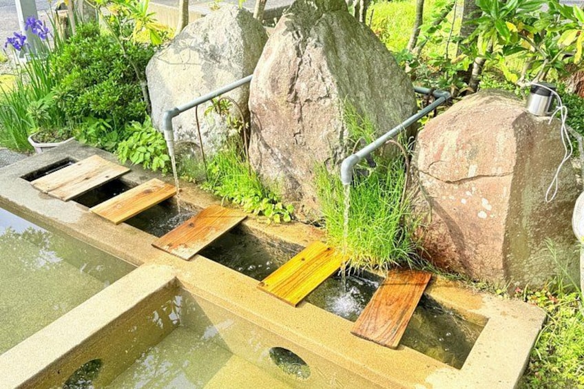 A wooden water feature with a small stream, surrounded by rocks and greenery. 2