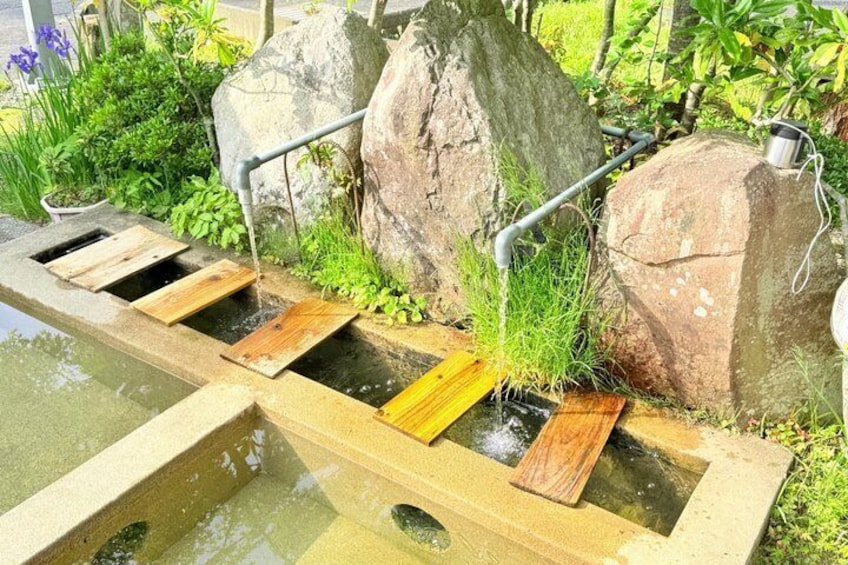 A wooden water feature with a series of steps leading into a pond, surrounded by rocks and greenery. 2