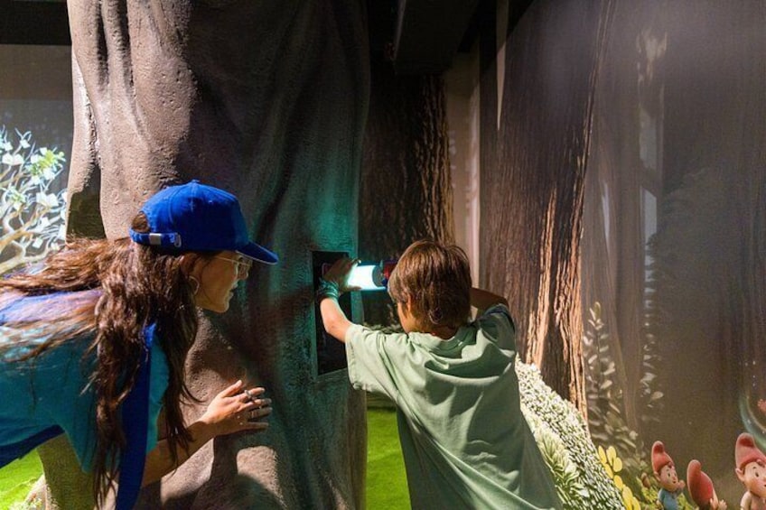 Two people interacting with a large tree-like structure in an indoor exhibit. 3