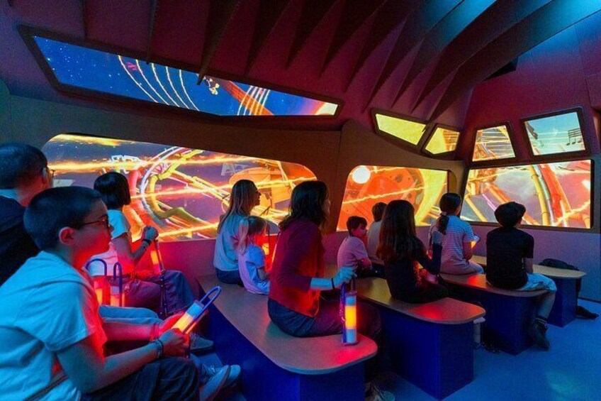 A group of people seated in a room with a large, illuminated, abstract artwork on the wall. 4