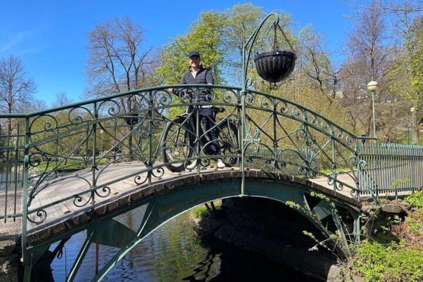 A wrought iron bridge over a canal with a person riding a bicycle. 5