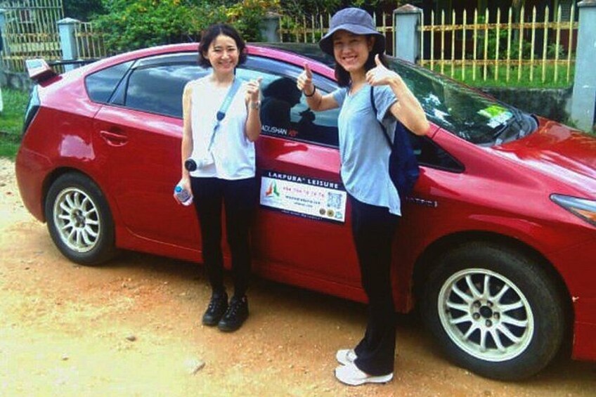 Two people standing next to a red car with a sign on the side. 4