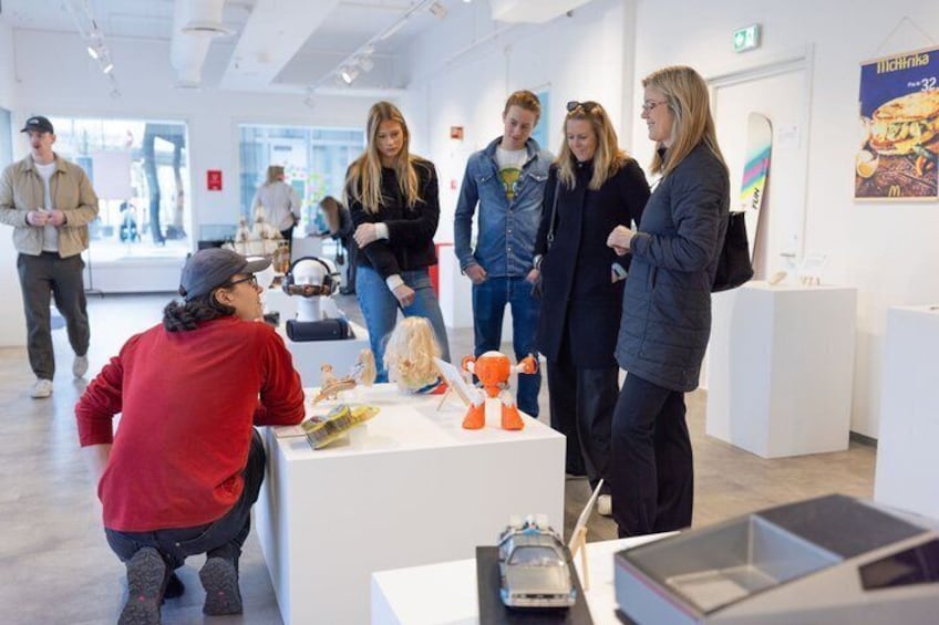 An indoor exhibition with people observing various displays. 3