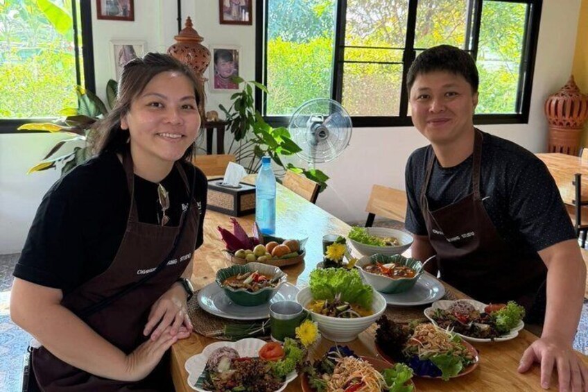Two people seated at a table with various dishes of food. 1